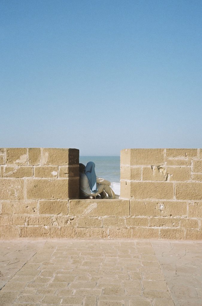 Fotografia d'unes joves mirant el mar a Essaouira, Marroc, capturada per Júlia Olivé Studio, artista multidisciplinar especialitzada en fotografia, disseny i il·lustració.